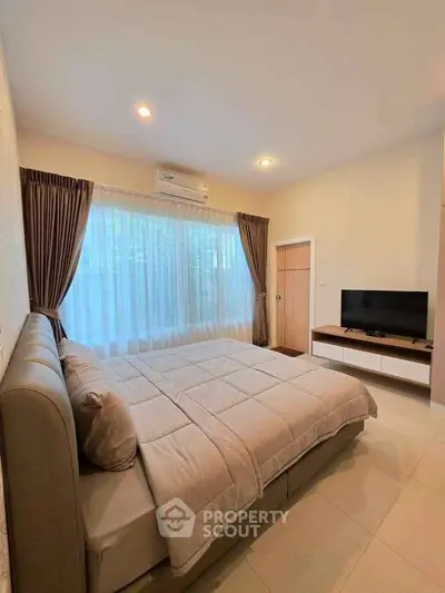 Cozy bedroom with large window and modern furnishings in a stylish apartment.