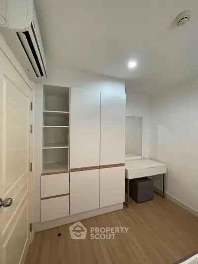 Modern bedroom with sleek white wardrobe and minimalist vanity in a cozy apartment.
