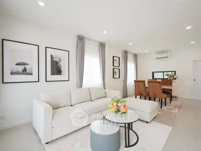 Elegant living room with modern decor, featuring a cozy white sofa and stylish dining area.
