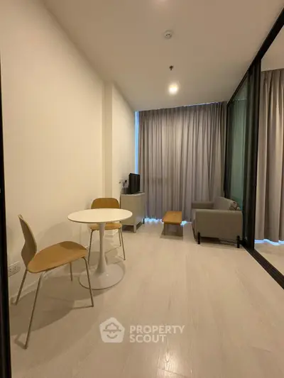 Modern living room with minimalist furniture and large window for natural light.