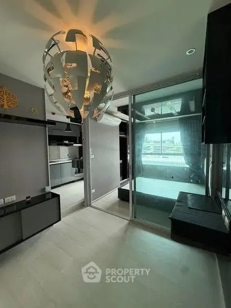 Modern living room with unique chandelier and sliding glass doors leading to a balcony with city view.