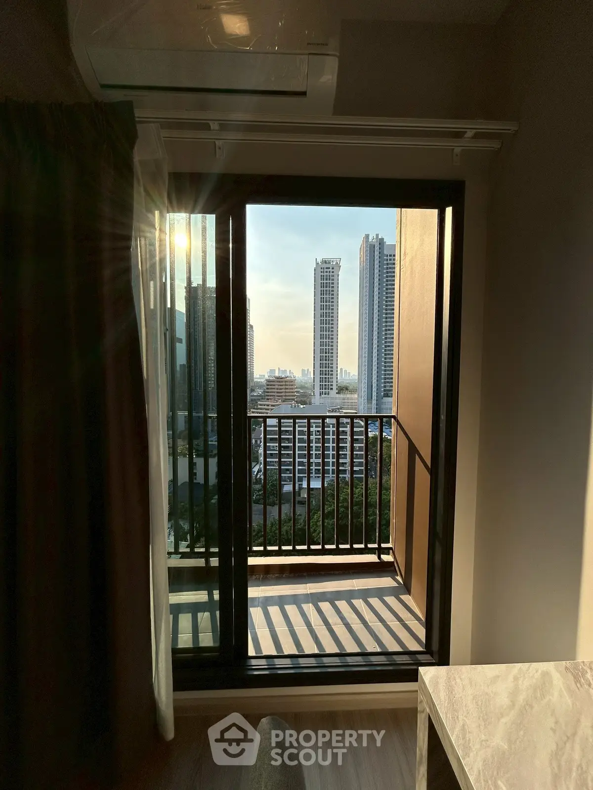 Stunning high-rise apartment with balcony offering breathtaking city views at sunset.