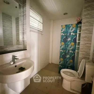 Modern bathroom with stylish sink and vibrant shower curtain in a cozy home.