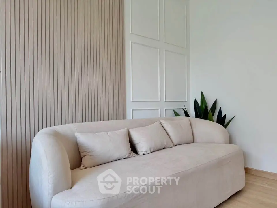 Elegant modern living room with stylish beige sofa and decorative wall panels.