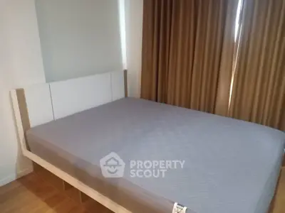 Spacious bedroom with modern design and large bed, featuring elegant curtains and wooden flooring.