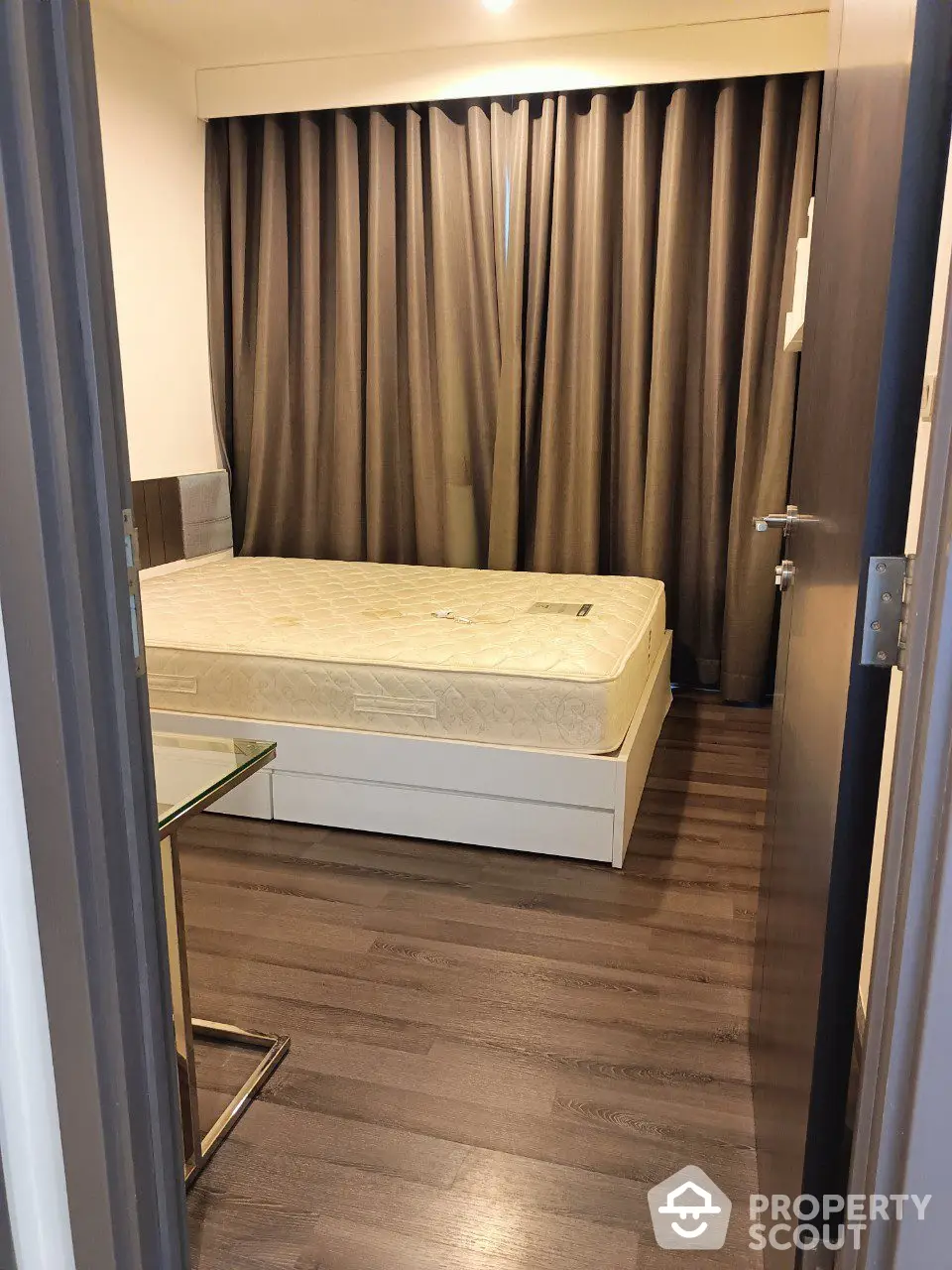 Cozy bedroom with elegant dark curtains and a large comfortable bed, featuring sleek wooden flooring and a minimalist design, perfect for restful nights.