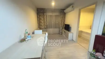 Modern living room with dining area and bedroom view, featuring sleek furniture and ambient lighting.