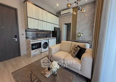 Modern living room with open kitchen, featuring stylish decor and appliances in a cozy apartment setting.