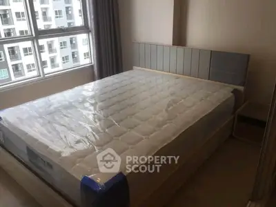 Spacious bedroom with large window and modern bed in a high-rise apartment.