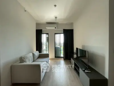 Modern living room with sleek design, featuring a comfortable sofa and large windows offering city views.
