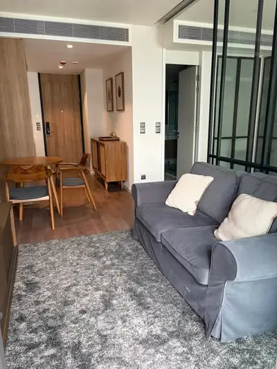 Modern living room with cozy gray sofa and stylish dining area in open layout apartment.
