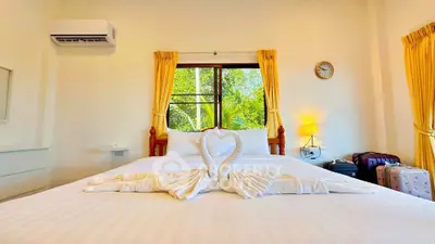 Cozy bedroom with elegant decor and large window view, featuring swan towel art on a plush bed.