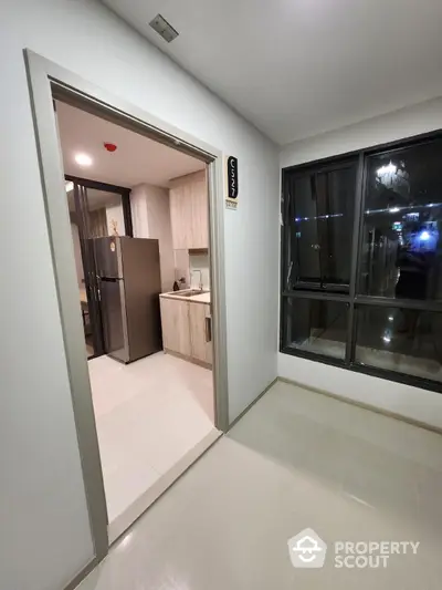 Modern kitchen with sleek appliances and large windows in a contemporary apartment.