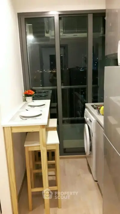Compact modern kitchen with balcony view, featuring sleek appliances and cozy dining area.