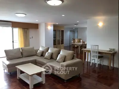 Spacious living room with modern furniture and dining area, featuring elegant wooden flooring.