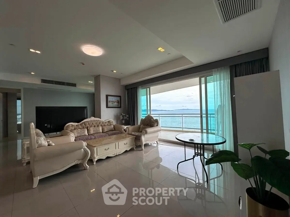 Luxurious living room with elegant furniture and stunning ocean view from large balcony.