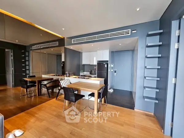 Modern open-layout kitchen with sleek design and dining area, featuring wooden flooring and stylish decor.