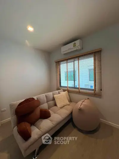 Cozy small living room with modern sofa and air conditioning, perfect for relaxation.