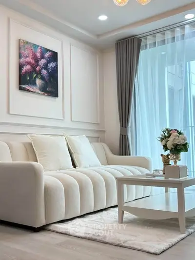 Elegant living room with plush sofa, chic decor, and natural light from large windows.