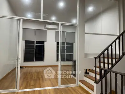 Spacious modern interior with wooden flooring and glass partitions, ideal for versatile living spaces.