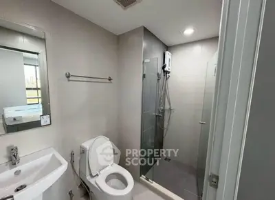 Modern bathroom with glass shower and sleek fixtures in contemporary apartment.