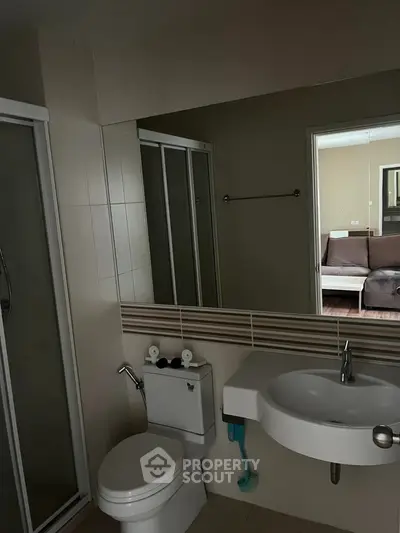 Modern bathroom with sleek fixtures and large mirror in contemporary apartment.