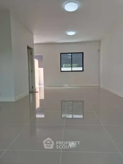 Spacious modern living room with glossy tiled floors and ample natural light.