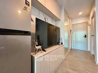 Modern living room with sleek TV unit and stainless steel fridge in stylish apartment.