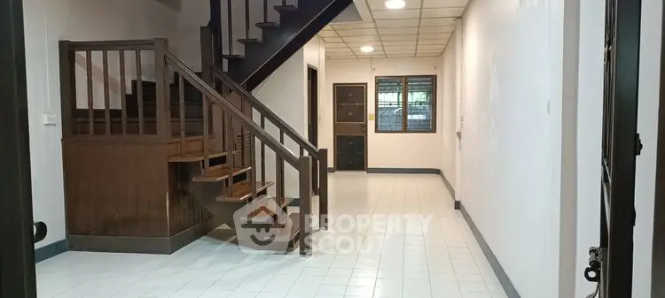 Spacious interior with wooden staircase and tiled floor, ideal for modern living.