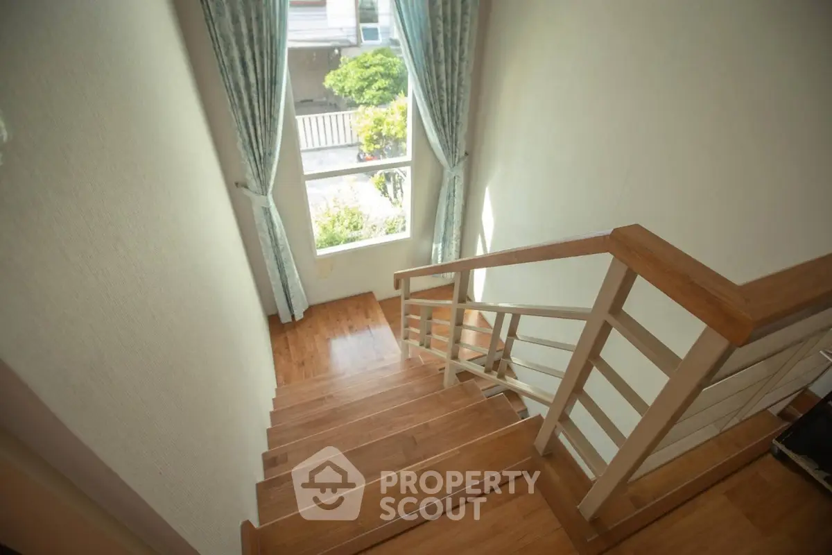 Elegant wooden staircase with natural light and garden view, perfect for modern homes.