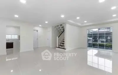 Spacious modern living room with glossy tile flooring and staircase, perfect for family gatherings.