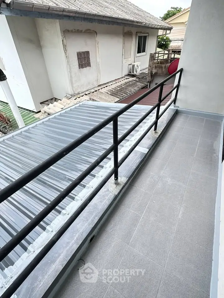 Spacious balcony with modern railing overlooking neighboring rooftops, perfect for relaxation and outdoor enjoyment.