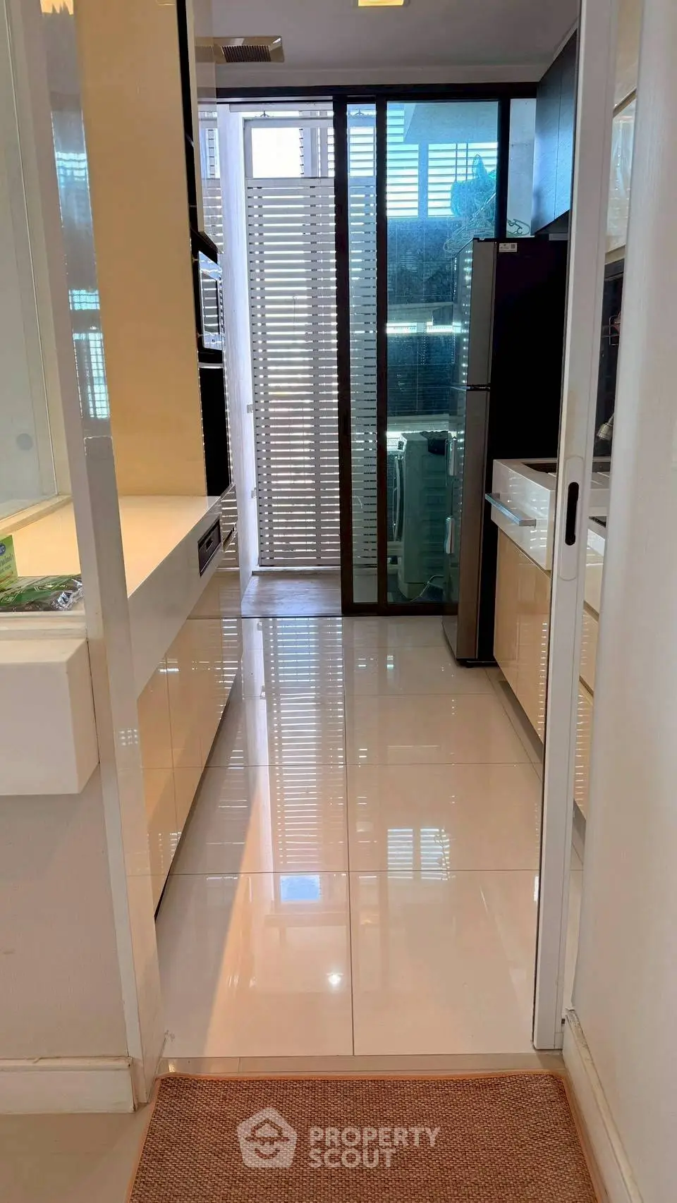 Modern kitchen with sleek design and glossy finishes, featuring a closed layout and ample natural light.