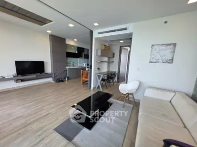 Modern open-layout living room with sleek furniture and integrated kitchen area, perfect for contemporary living.
