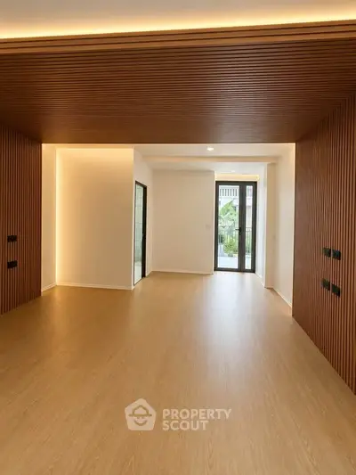 Spacious modern living room with wooden accents and large windows for natural light.