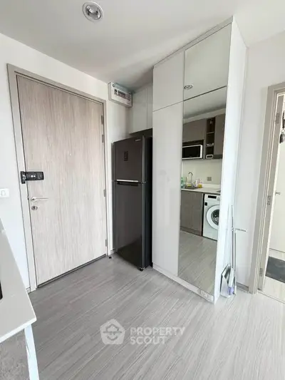 Modern kitchen with sleek appliances and minimalist design, featuring a black fridge and washing machine.