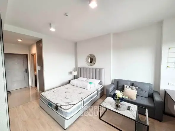 Modern bedroom with stylish decor and cozy seating area in a bright apartment.