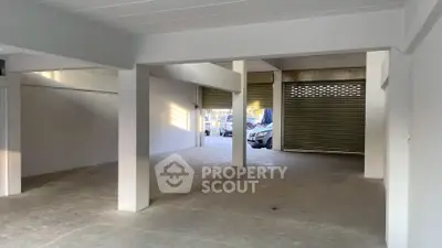 Spacious open garage with concrete flooring and roll-up doors, ideal for parking or storage.