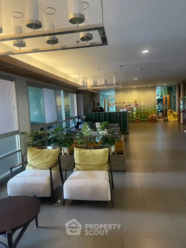 Modern lobby with stylish seating and lush greenery in a contemporary building.