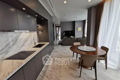 Luxurious open-layout kitchen and living room with marble finishes and modern furnishings.