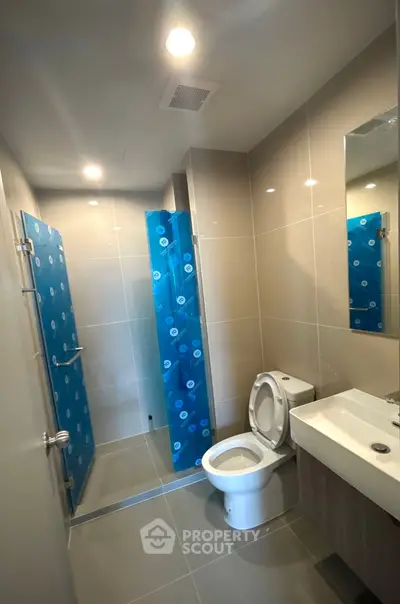 Modern bathroom with sleek design, featuring a glass shower enclosure and contemporary fixtures.