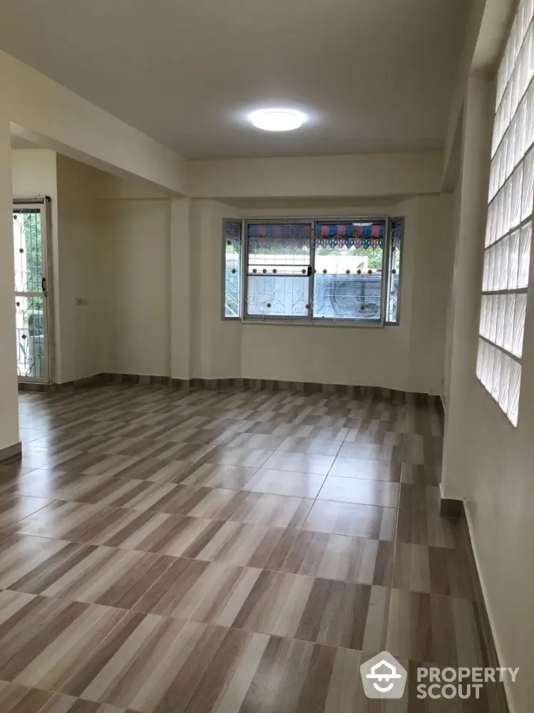 Spacious living room with large window and modern tiled flooring