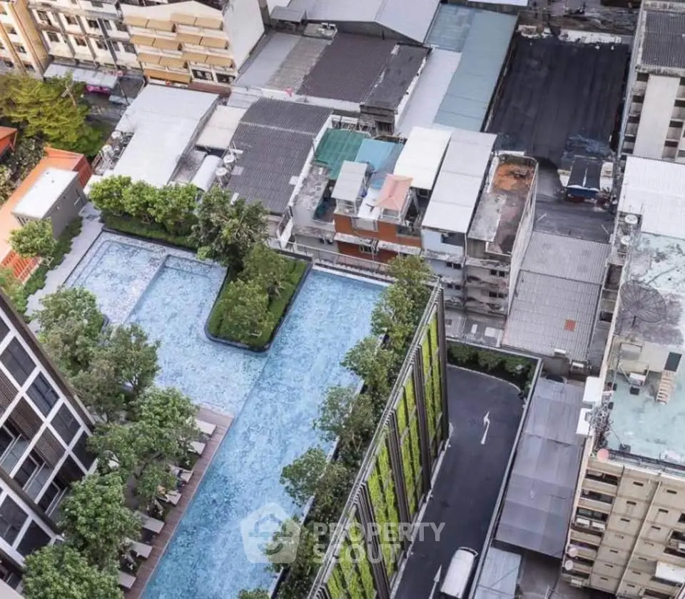 Stunning aerial view of modern urban residential complex with rooftop pool and lush greenery.