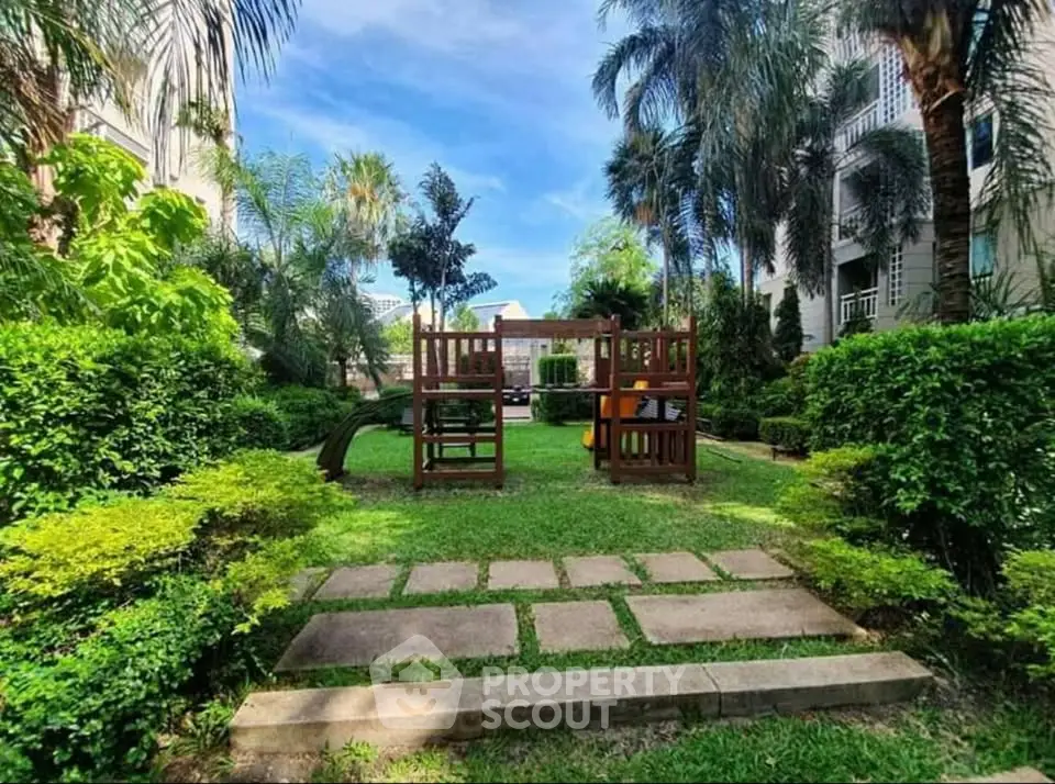 Lush garden with playground in residential complex, perfect for family living.