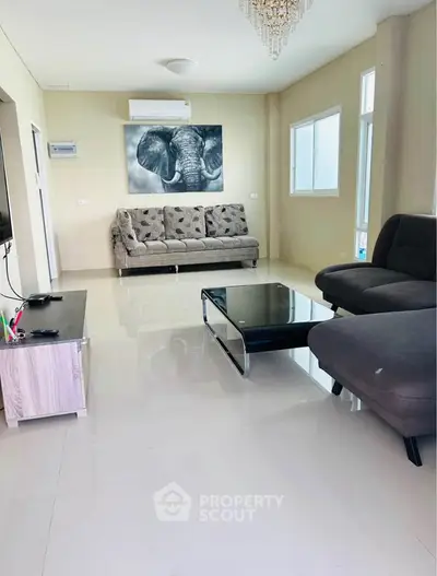 Spacious modern living room with elegant decor and ample natural light, featuring stylish furniture and a chic elephant artwork.