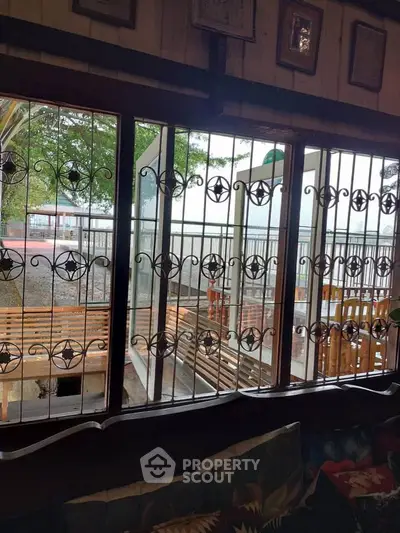 Charming interior with decorative window grills and cozy seating area overlooking a serene outdoor view.