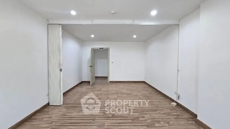 Spacious empty room with modern flooring and recessed lighting, perfect for customization.