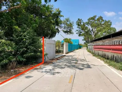 Scenic road view with lush greenery and clear blue sky, ideal for real estate development.