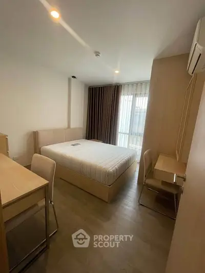 Modern bedroom with minimalist design, featuring a comfortable bed, study desk, and natural light from large window.