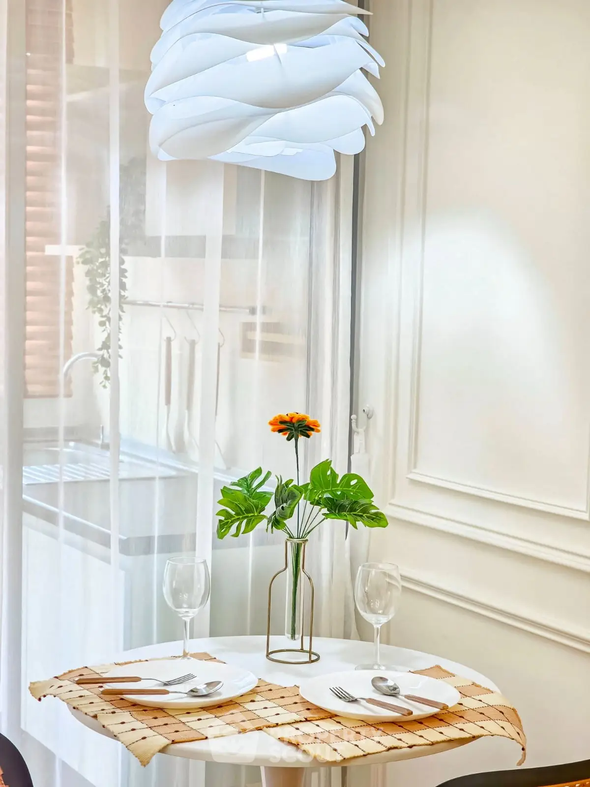 Charming dining nook with elegant table setting and modern lighting in a cozy kitchen corner.